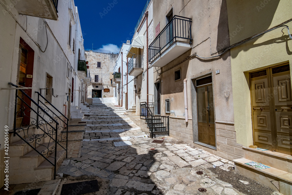 Mesagne. Puglia, Italy under the clear blue sky of a sunny summer day, travel photography, street view of narrow pedestrian street covered by stone tiles. No people in the frame