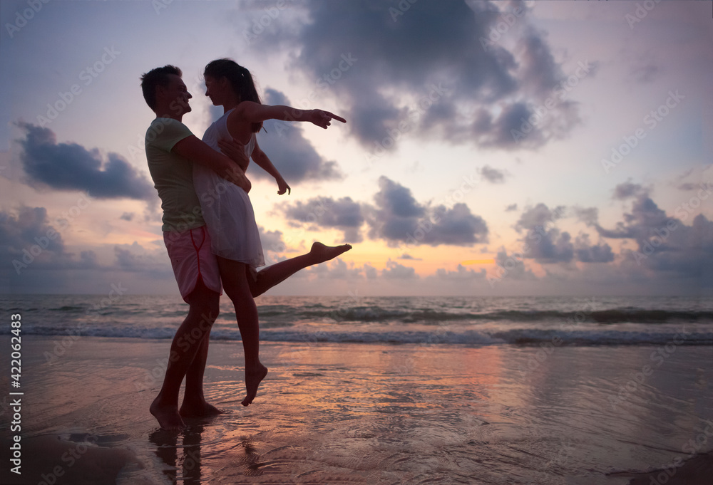 Fototapeta premium The image of silhouette of two people in love at sunset in Thailand