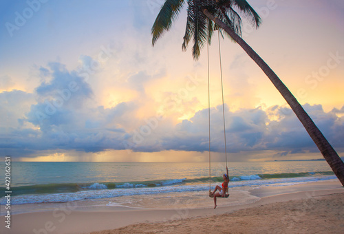 Young Woman swinging at tropical beach in Thailand