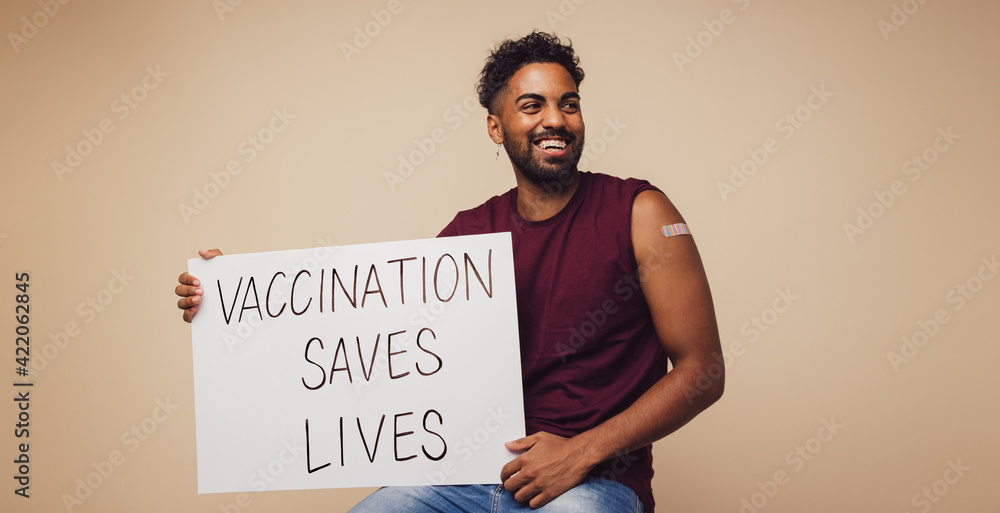 Man holding Vaccination saves lives placard - obrazy, fototapety, plakaty 