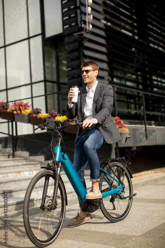 Young businessman on the ebike with takeaway coffee cup