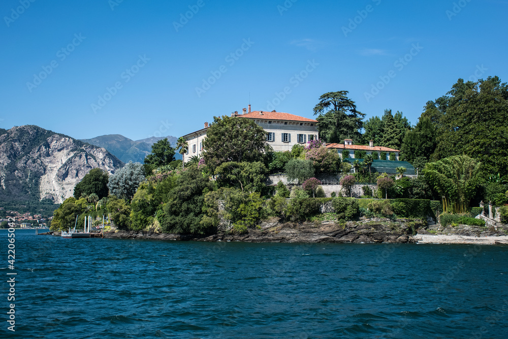 Ancient buildings are buried in the shade of coastal trees on one of the Borromean Islands on Lake Maggiore in Italy