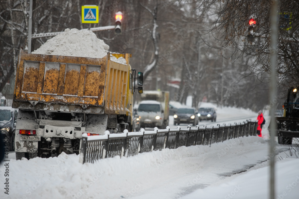 Naklejka premium Communal services worker sweeps snow from road in winter, Cleaning city streets and roads during snowstorm. Moscow, Russia