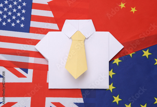 Origami shirt with tie on the background of many flag. Politics or business concept