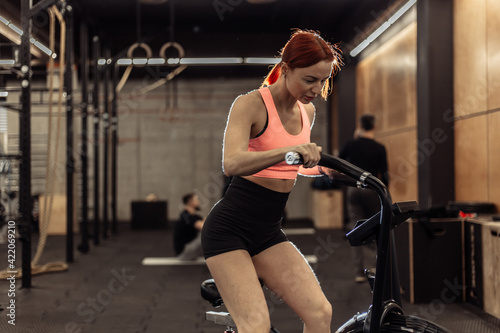 Redhead fit woman doing intense cardio training on exercise bike