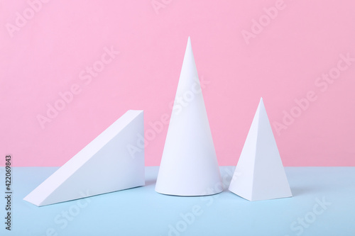 White geometric figures on a blue-pink pastel background. Composition of different geometric objects. Concept art. Abstract background, minimalism