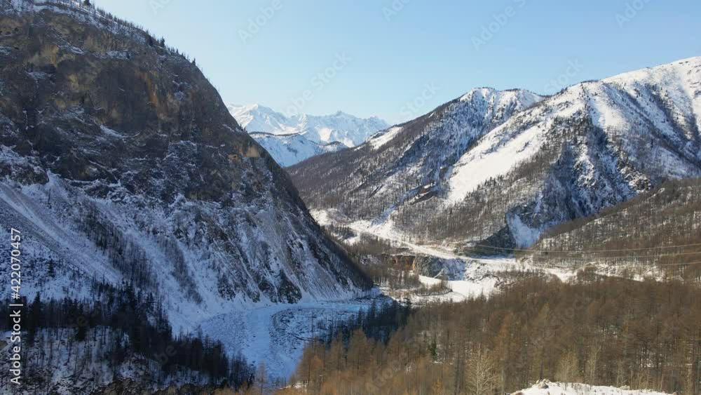 Valley among Sayan Mountains with Frozen Water Surface in Winter. Irkut River Covered with Ice and Snow, Russia Valley among Sayan Mountains with Frozen Water Surface in Winter. Irkut River Covered with Ice and Snow, Russia