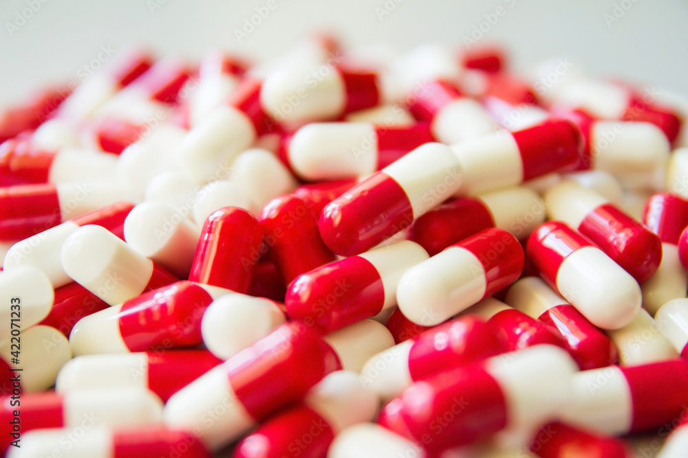 Red and white pills on the table. Closeup. Medical capsules. Medicine. Pharmaceuticals. Bioactive additives. Vitamins. Illness. Disease. Tablets for health. Red and white pills on the table. Closeup. Medical capsules. Medicine. Pharmaceuticals. Bioactive additives. Vitamins. Illness. Disease. Tablets for health.