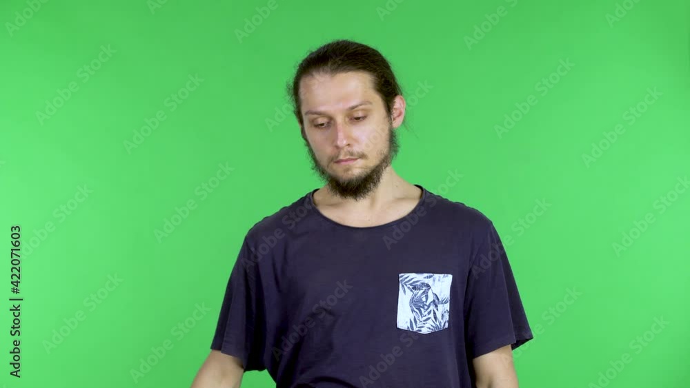 Caucasian male relieves stress by yawning. The man shows a tired gesture, covering his mouth with his hand and sneezing. A brunette man with a beard poses in the studio on a green screen. Close up. Caucasian male relieves stress by yawning. The man shows a tired gesture, covering his mouth with his hand and sneezing. A brunette man with a beard poses in the studio on a green screen. Close up.