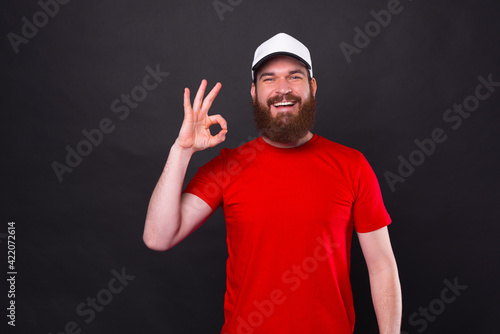 Portrait of amazed young bearded smiling man showing OK gesture
