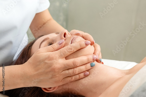 Facial massage close-up. Young  beautiful girl at spa procedures. Skin care  oriental massage treatments  beauty treatments.