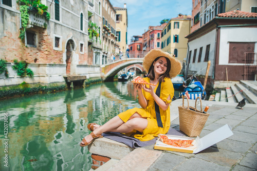 woman sitting on pond with view of venice canal eating pizza