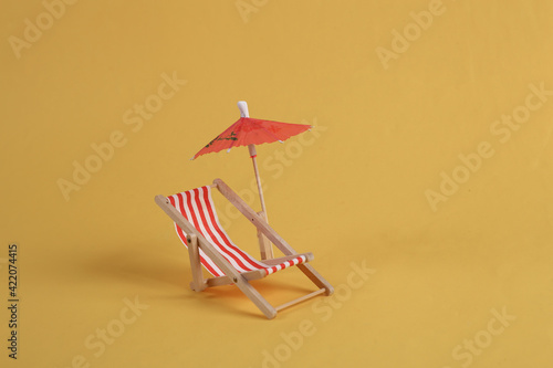 Deck chair with umbrella on a yellow background. Beach rest