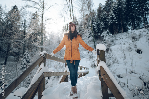 Femme jeune et belle en hiver dans la forêt froide et enneigée photo