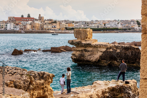 Otranto. Tratto roccioso della costa con persone sullo sfondo della Città. photo