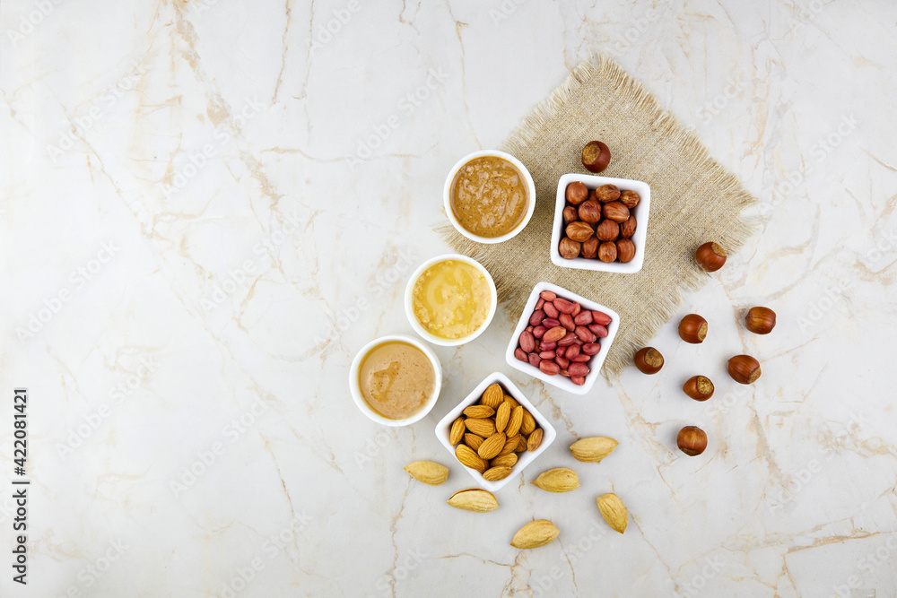 Nuts butter in bowls with ingredients. Homemade raw organic peanut, hazelnut, almond paste or butter. Copy space. Top view. Nuts butter in bowls with ingredients. Homemade raw organic peanut, hazelnut, almond paste or butter. Copy space. Top view.