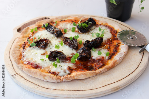 Pizza on a wooden board with mozzarella, mini arugula.