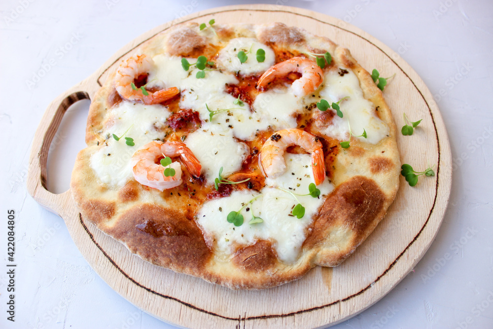 Pizza on a wooden board with mozzarella, mini arugula. Pizza on a wooden board with mozzarella, mini arugula.