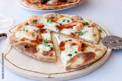 Pizza on a wooden board with mozzarella, mini arugula.