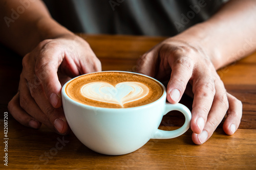 hand hold cup of coffee close-up with heart latte art 