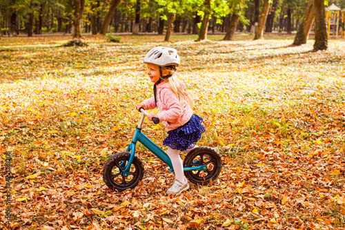 Fototapeta Naklejka Na Ścianę i Meble -  Lovely girl riding balance bike in atumn park