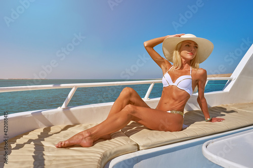 Young woman on the deck of a boat in open sea at sunny summer day