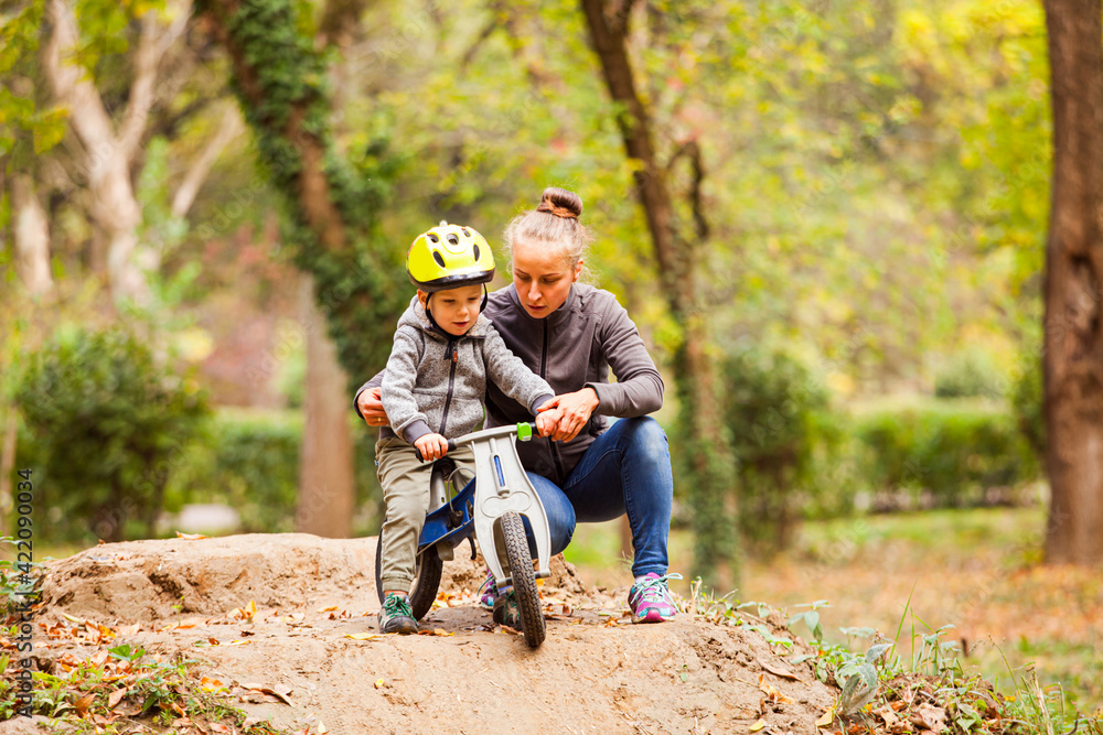 Supportive mom encourages boy to ride down the hill