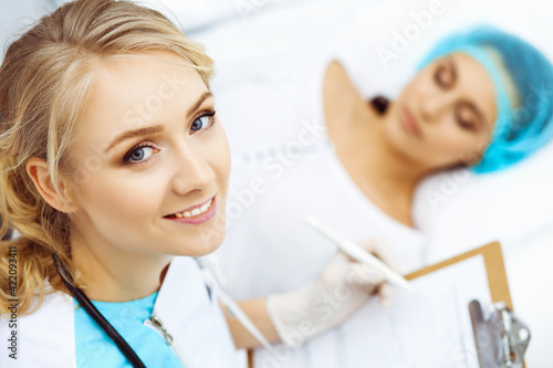 Female doctor and young woman patient in hospital. Physicians examine girl lying at the bed, view from above