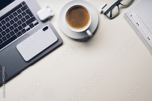 Workplace in office with white desk. Top view from above of keyboard with notebook and coffee. Space for modern creative work of designer. Flat lay with blank copy space. Business and finance concept.