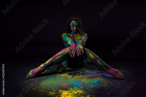 Bright colorful body art on black background, sexy nude woman painted with powder paints