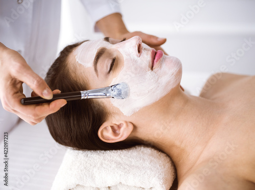 Beautiful brunette woman enjoying applying cosmetic mask comfortable and bissfulle. Relaxing treatment in medicine and spa center concepts
