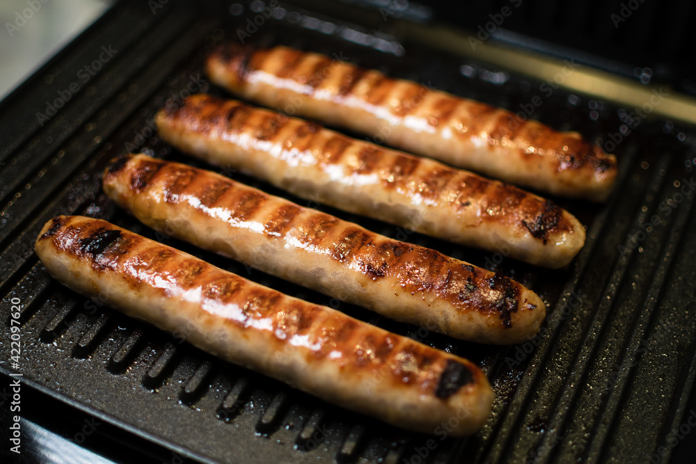 Grilled meat sausages for hot dog, kupaty, sausages, fatty food cooked on the barbecue, with fresh vegetables slicing, close-up Grilled meat sausages for hot dog, kupaty, sausages, fatty food cooked on the barbecue, with fresh vegetables slicing, close-up