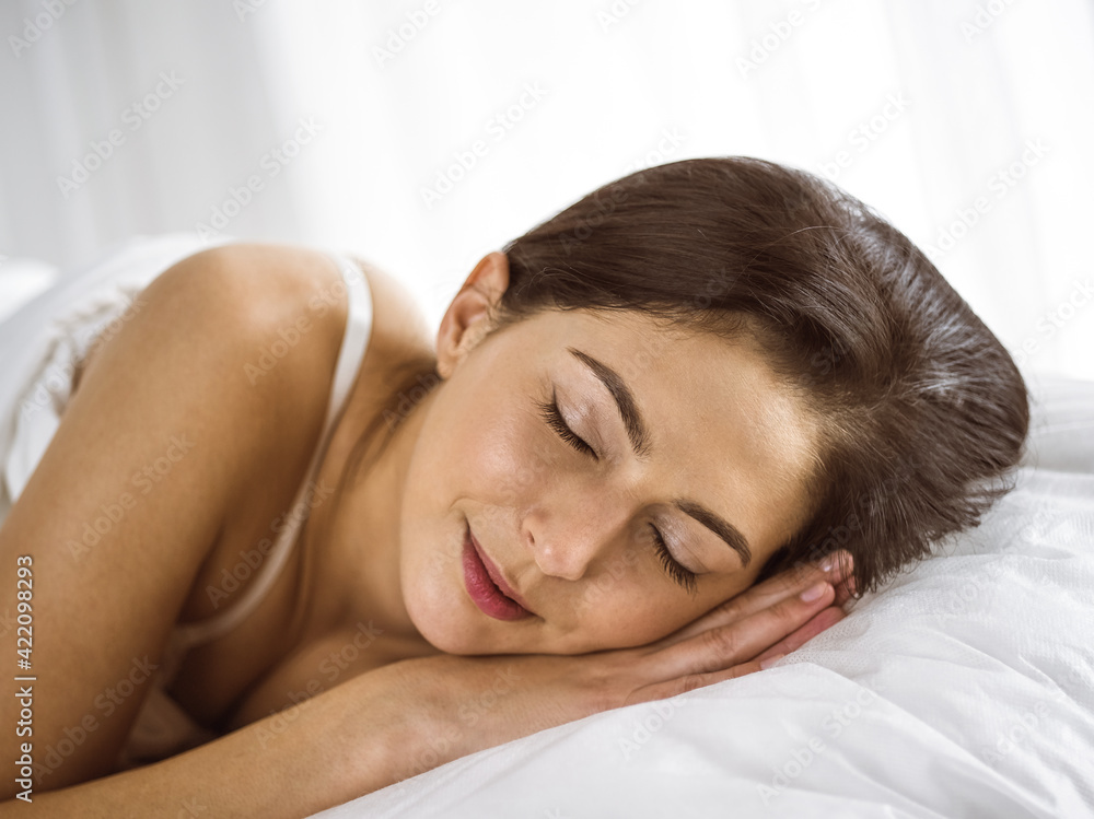 Beautiful young brunette woman sleeping while lying in bed comfortably and blissfully. Good morning concept Beautiful young brunette woman sleeping while lying in bed comfortably and blissfully. Good morning concept