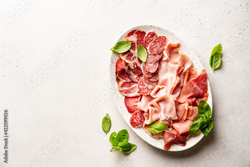 Appetizers with differents antipasti, charcuterie, snacks and red wine on white background. Sausage, ham, tapas, olives and crackers for buffet party. Top view, flat lay