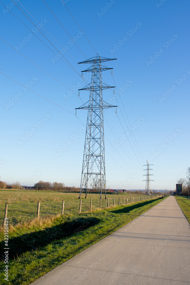Electricity pole for transportation of electricity in a meadow with a clear blue sky