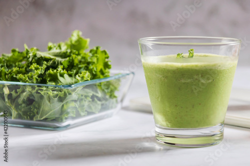 Healthy green kale smoothie with greek yogurt in a glass isolated on white table background, top view. Kale is considered a superfood because it's a great source of vitamins and minerals.