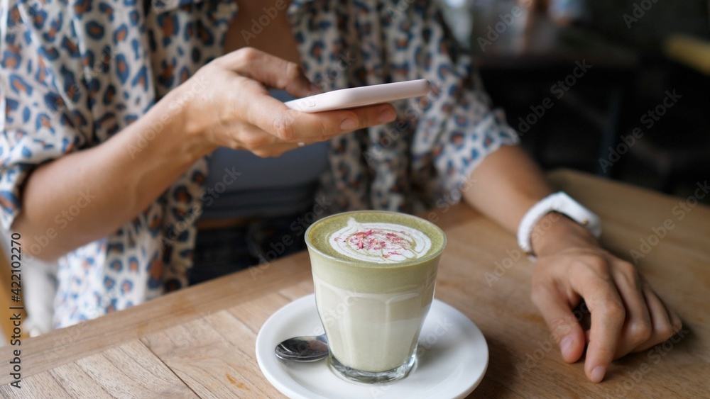 Blogger taking a picture of green tea matcha latte decorated with flowers. Healthy organic plant based drinks Blogger taking a picture of green tea matcha latte decorated with flowers. Healthy organic plant based drinks