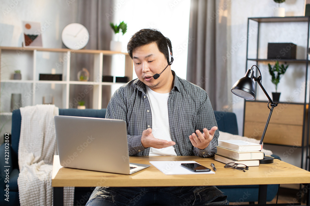 Asian man using headset and laptop for video chat Asian man using headset and laptop for video chat