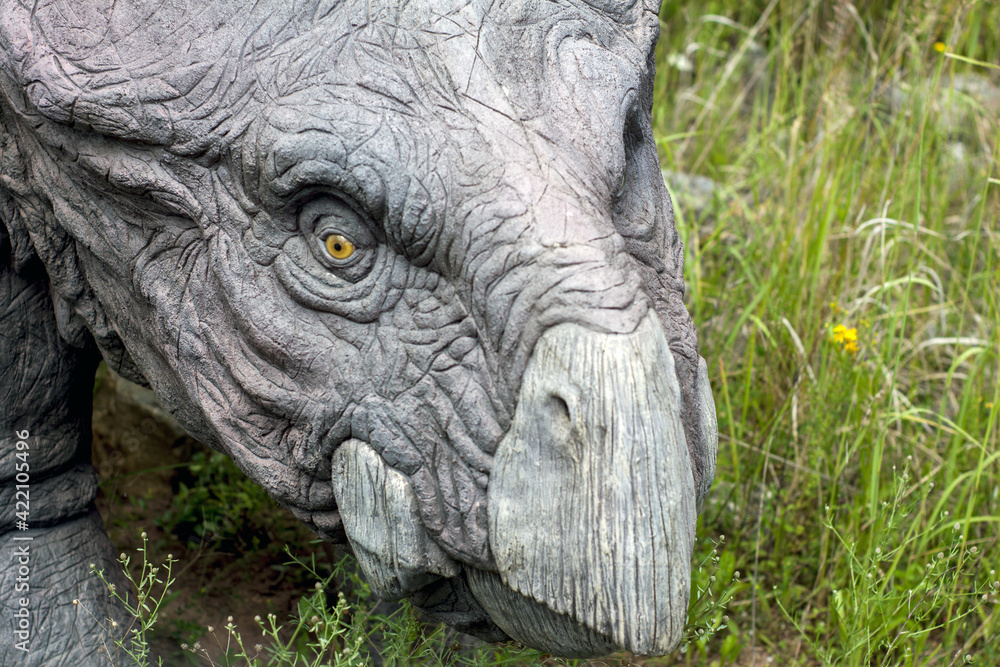 Fototapeta premium A model of a prehistoric dinosaur made available to visitors to a Jurassic park to learn about the history of many millions of years. In the background, vegetation and terrain resembling the natural h