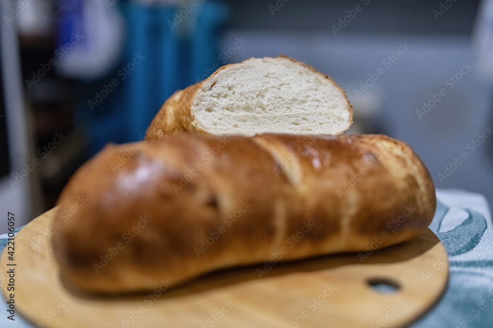 A loaf of fresh white wheat bread on a wooden background.