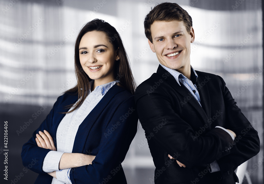 Friendly young colleagues are standing as a team with crossed arms in a modern office. Portrait of successful business people at work Friendly young colleagues are standing as a team with crossed arms in a modern office. Portrait of successful business people at work