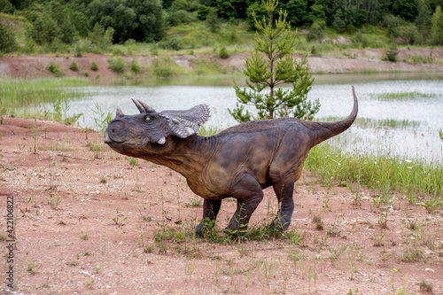 A model of a prehistoric dinosaur made available to visitors to a Jurassic park to learn about the history of many millions of years. In the background, vegetation and terrain resembling the natural h