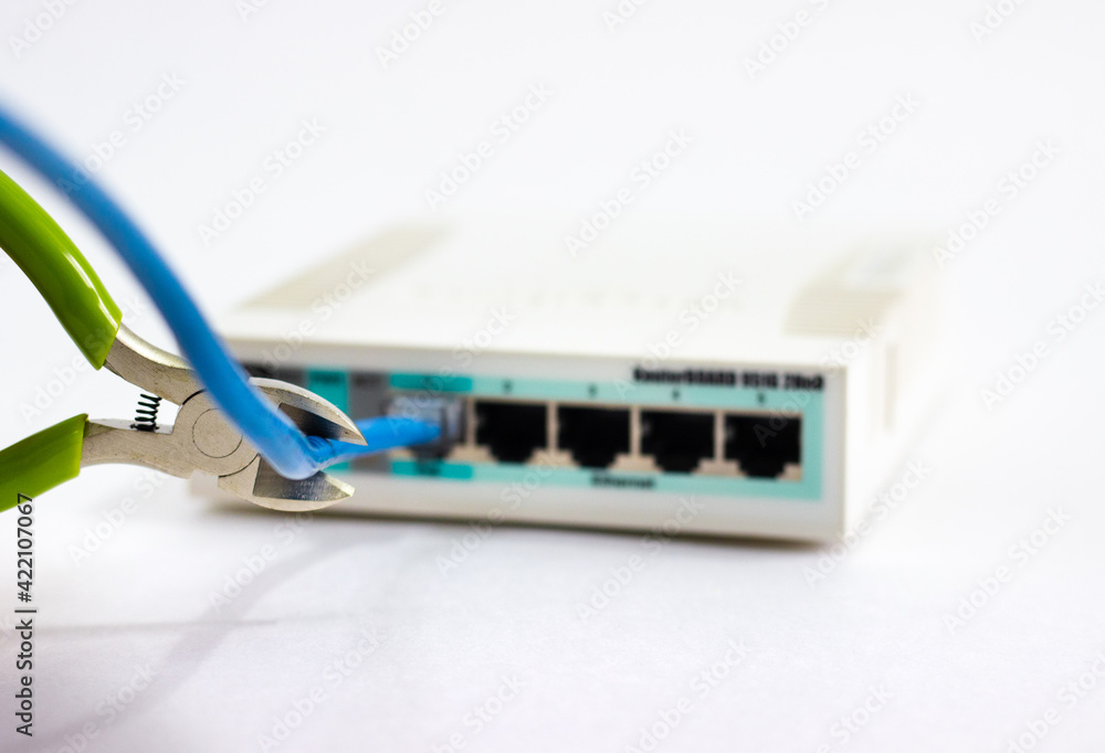 Cuts cable on router. Man cuts cord of Wi-Fi router. White router with cut cord. Side cutters cut cable on white background. Network cable in router is damaged. Hand cuts cable. Cuts cable on router. Man cuts cord of Wi-Fi router. White router with cut cord. Side cutters cut cable on white background. Network cable in router is damaged. Hand cuts cable.