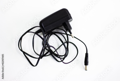 Black power adapter on white background. Charging adapter with cable. DC + 5 ~ 9V 5.5 * 2.1MM adapter on white background. Black power supply with cable on white background.
