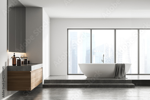 Bathtub and sinks with mirror in light bathroom interior with window