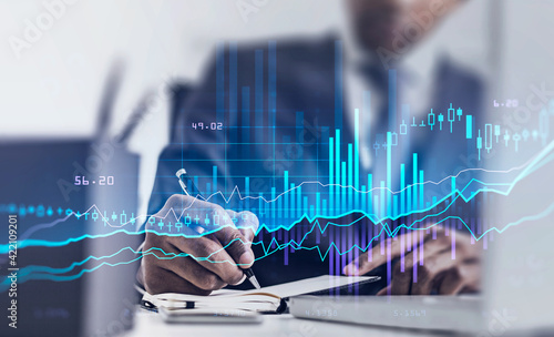 Man in office room, graph changes lines and bars with numbers photo