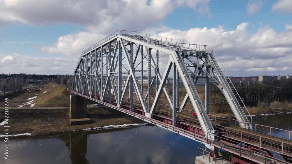 Metal railway train bridge over the river Belarus Orsha Dnieper River. early spring Aerial footage from a drone flying close along the bridge Metal railway train bridge over the river Belarus Orsha Dnieper River. early spring Aerial footage from a drone flying close along the bridge