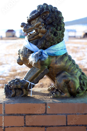 Buddhist Snow Lion bronze sculpture protecting temple entrance. Beautifully detailed sculpture mythological beast with strong paws and claws  photo