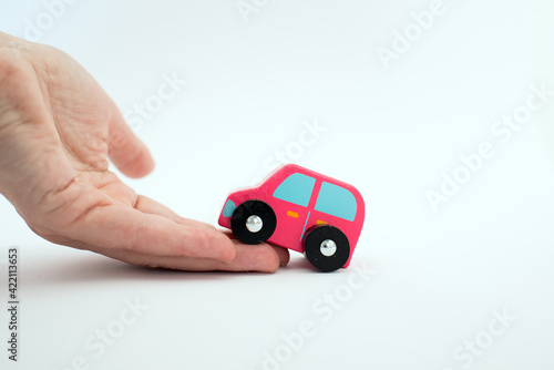 Close up of a caucasian beautiful hand helping a pink car to go up.White background. Conceptual for help.