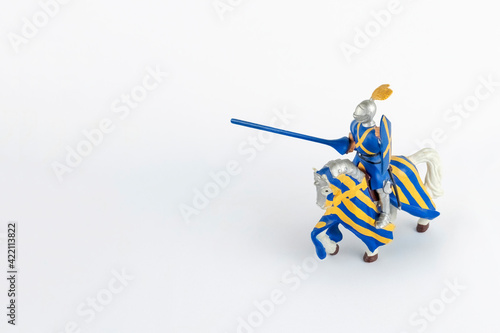 Medieval knight with feathers on his helmet ready to fight on a war horse, isolated on white background with copy space.
